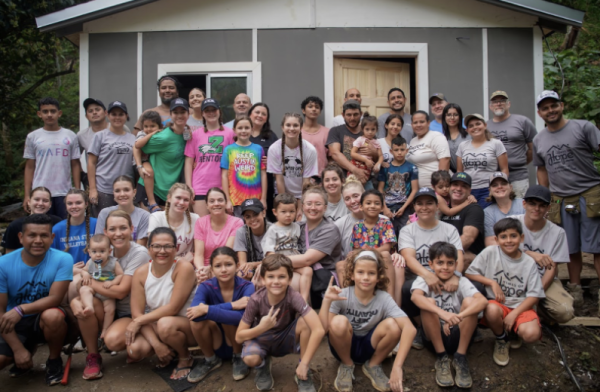 The mission trip group and families pose for a picture in front of the house they built. 